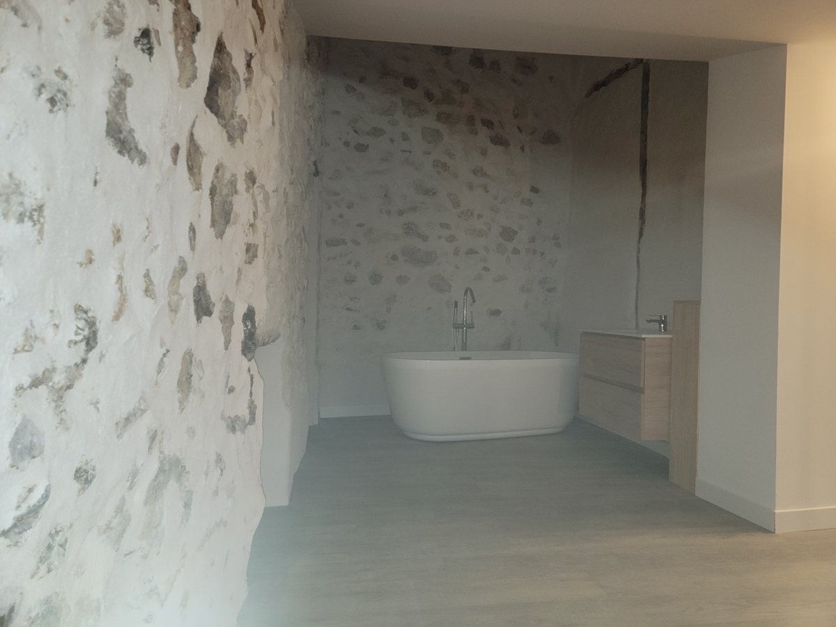 Baignoire îlot devant un mur en pierres apparentes
