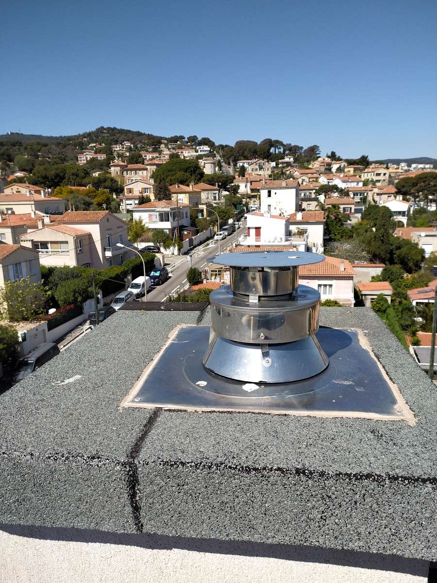 Chapeau de cheminée posé sur un toit-terrasse, vue sur la baie